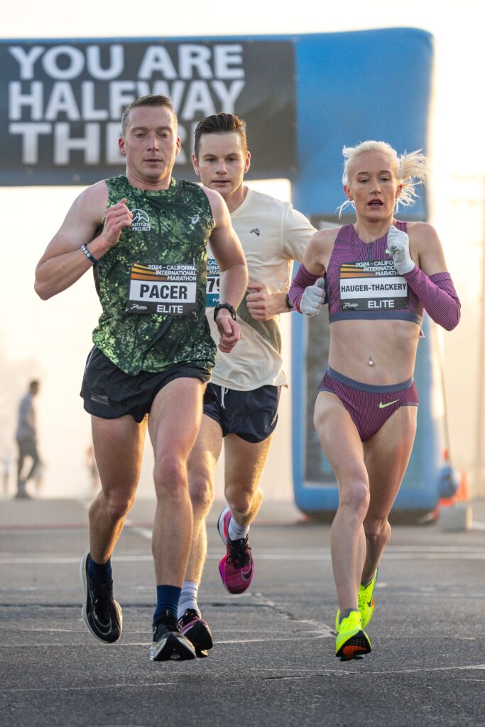 Elite marathon runners passing the halfway point during a race, demonstrating focus and endurance.